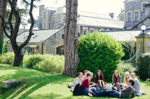 Students sitting in a circle on the grass on MIE campus